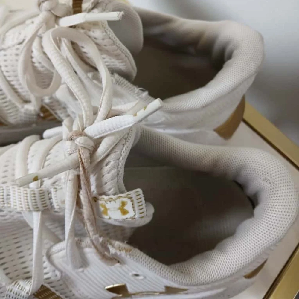 Under Armour White Sneakers with Gold Accents Size 10.